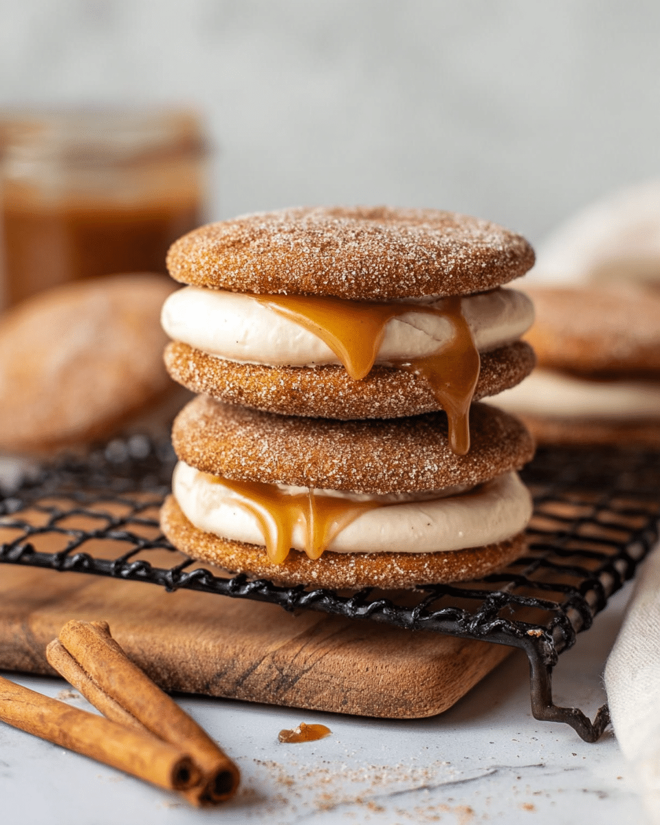 The image shows two sandwich-like desserts, each made of two round, cinnamon-sugar-coated cookies with a thick layer of light beige cream filling in between. The top sandwich has a small drip of caramel sauce oozing out from the cream. Both sandwiches rest on a black cooling rack placed over a wooden board, which sits on a white marbled textured surface. In the background, there is a blurry jar and a third sandwich. A cinnamon stick is placed in front on the surface. photo taken with an iphone --ar 4:5 --v 7