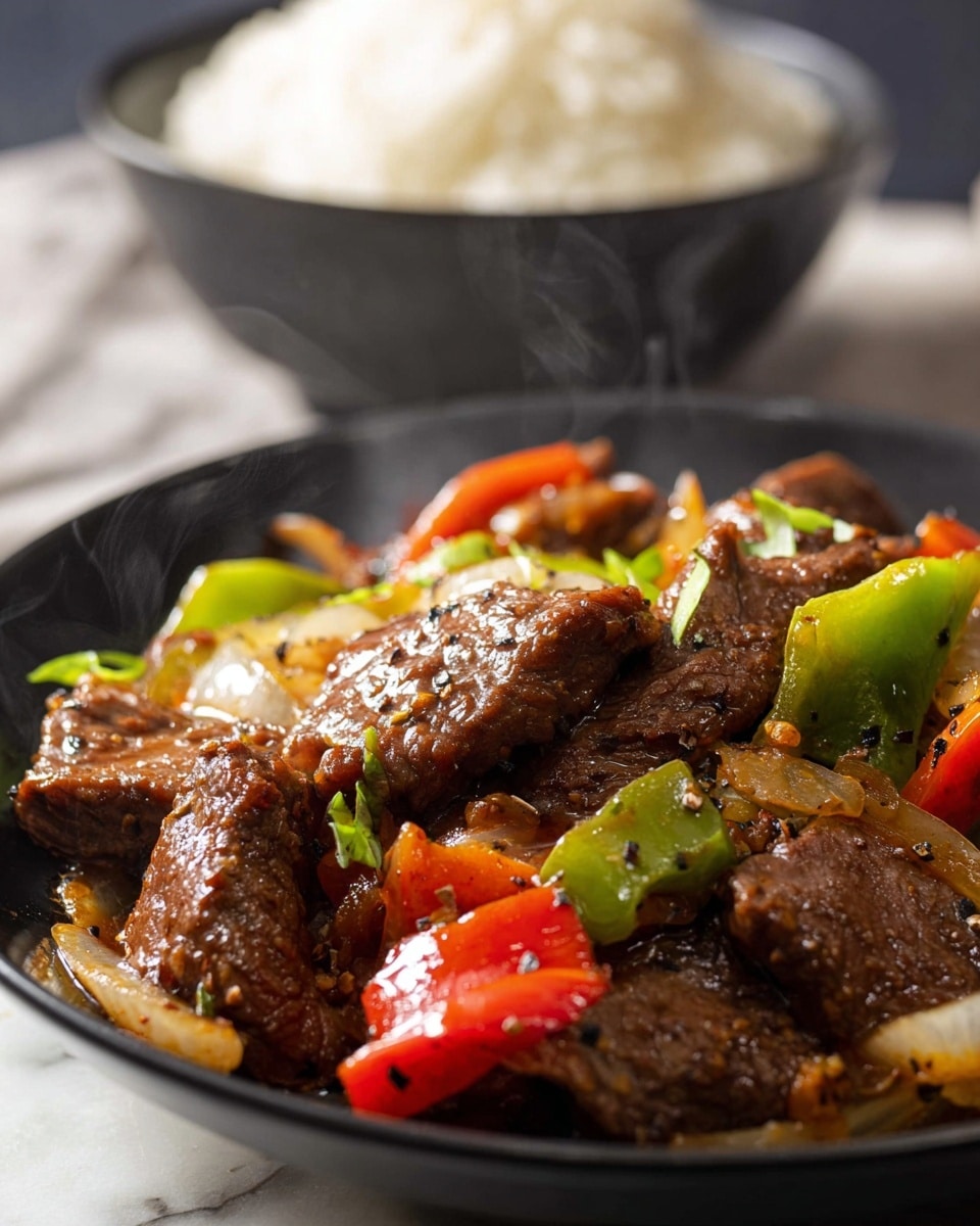 A close-up of a black bowl filled with a stir-fry dish consisting of several large pieces of brown, glossy beef, mixed with chunks of green bell peppers, red bell peppers, and sliced translucent onions, all coated in a shiny brown sauce with visible black pepper specks, with steam rising invitingly; in the background, out of focus, is a black bowl filled with fluffy white rice, sitting on a white marbled surface. photo taken with an iphone --ar 4:5 --v 7