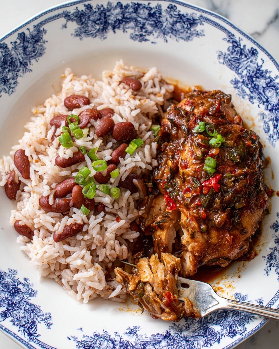 This image shows a white plate with blue floral patterns holding two main layers of food. On the left side, there is a layer of cooked rice mixed with red kidney beans, the rice grains are white and fluffy with pinkish red beans evenly spread. On the right side, there is a piece of cooked chicken covered with a dark reddish-brown sauce with bits of green herbs and red spices visible; the chicken has a moist, glossy texture and part of it is slightly pulled apart showing its juicy inside. Some sliced green onions are scattered over both the rice and chicken. There is a silver fork partly inserted into the chicken. The plate rests on a white marbled surface. photo taken with an iphone --ar 4:5 --v 7
