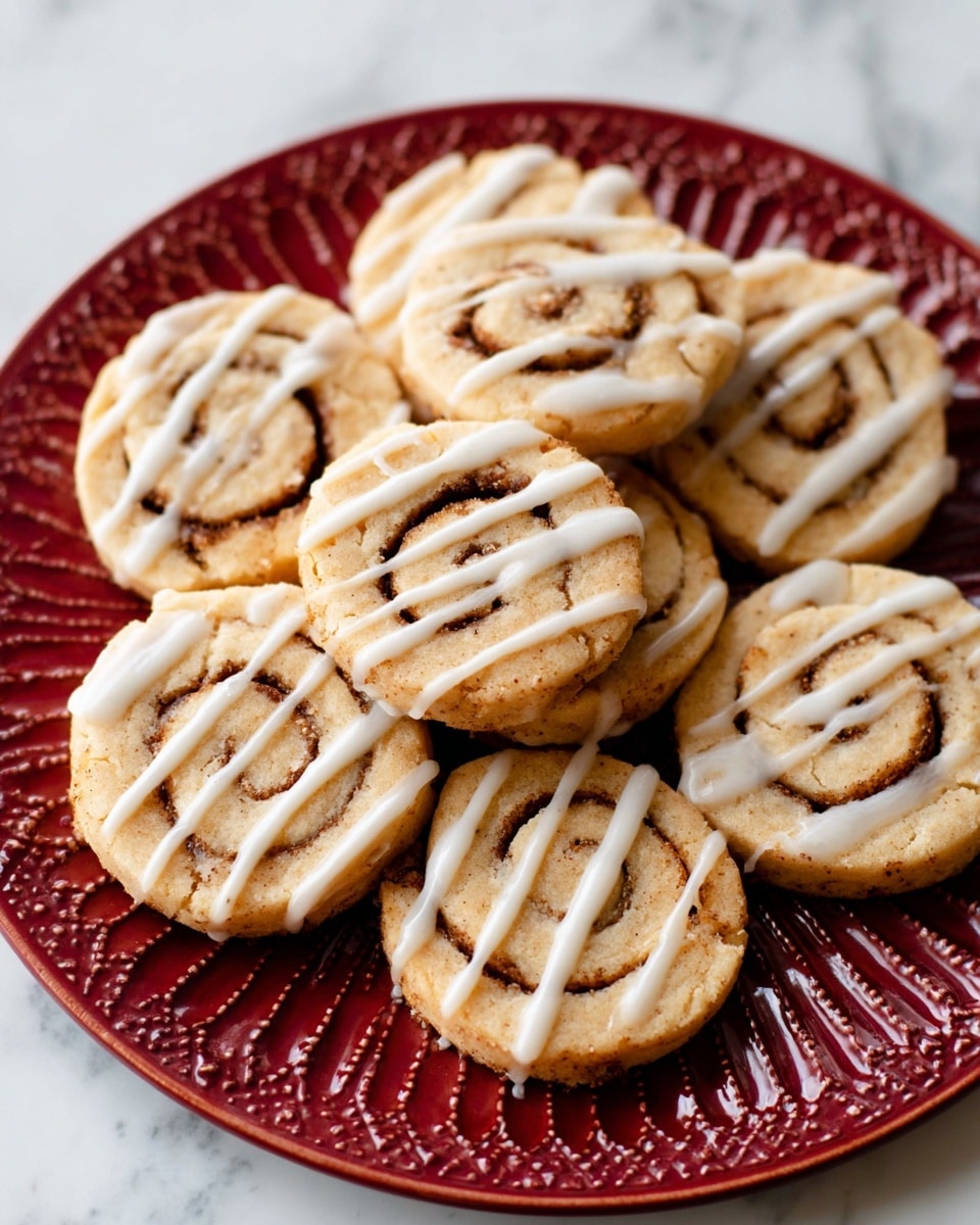 Seven cinnamon roll cookies are arranged in a loose circle on a white plate with a decorative raised pattern around the edge. Each cookie is a light golden color with visible dark brown cinnamon spiral swirls inside. They are topped with thin, white icing drizzled in uneven lines across the surface. The plate is set on a surface with a white marbled texture. photo taken with an iphone --ar 4:5 --v 7