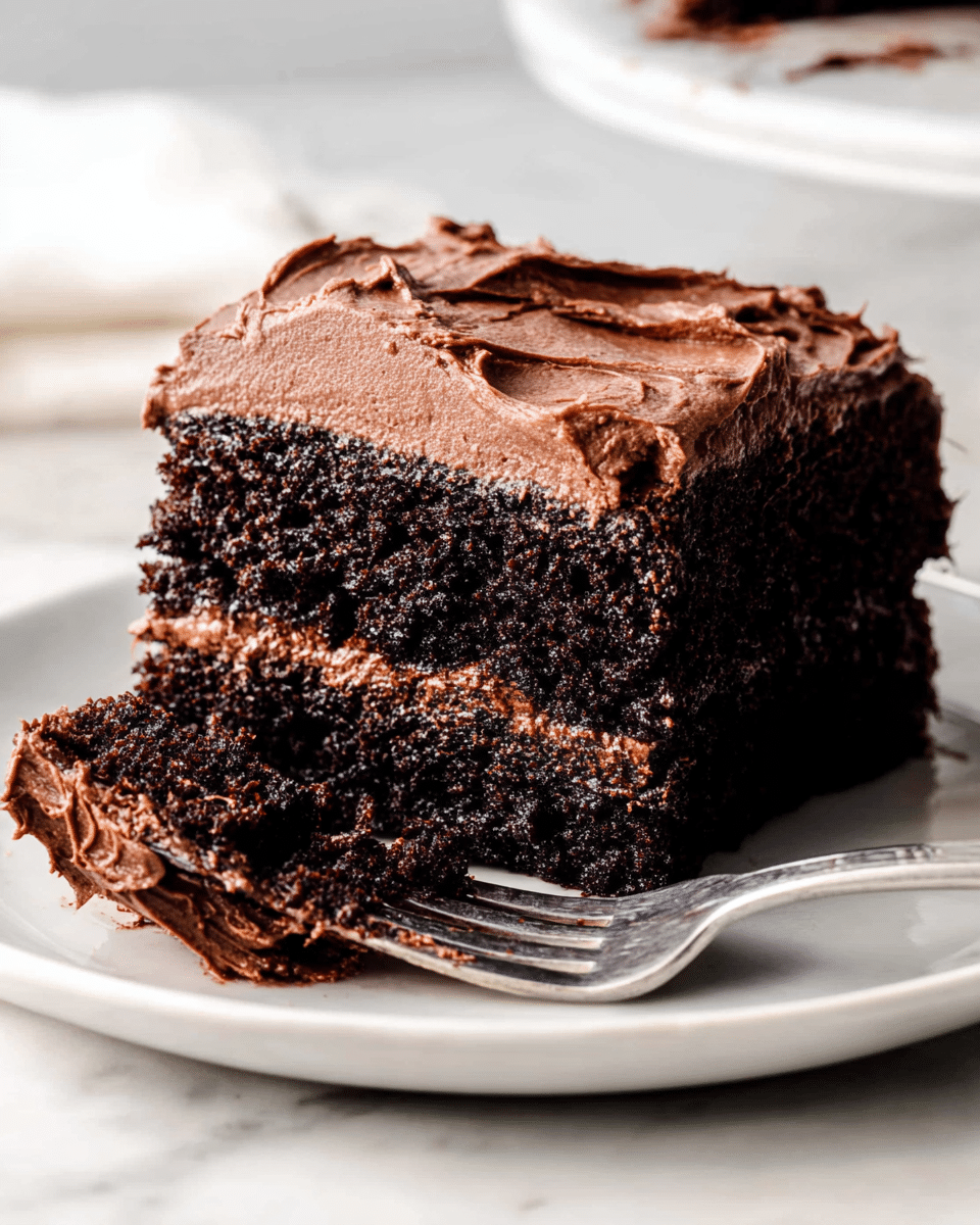 A square piece of chocolate cake with two distinct layers is centered on a stack of white plates; the bottom layer is dark brown, moist cake with a slightly crumbly texture, topped by a thick, smooth layer of rich, swirled chocolate frosting in a lighter brown shade. A silver fork rests diagonally on the plates beside the cake. In the background, there is a white plate with another piece of cake and a metal baking tray holding more pieces, all set on a white marbled surface. The scene has soft, natural lighting highlighting the texture of the cake and frosting. Photo taken with an iphone --ar 4:5 --v 7