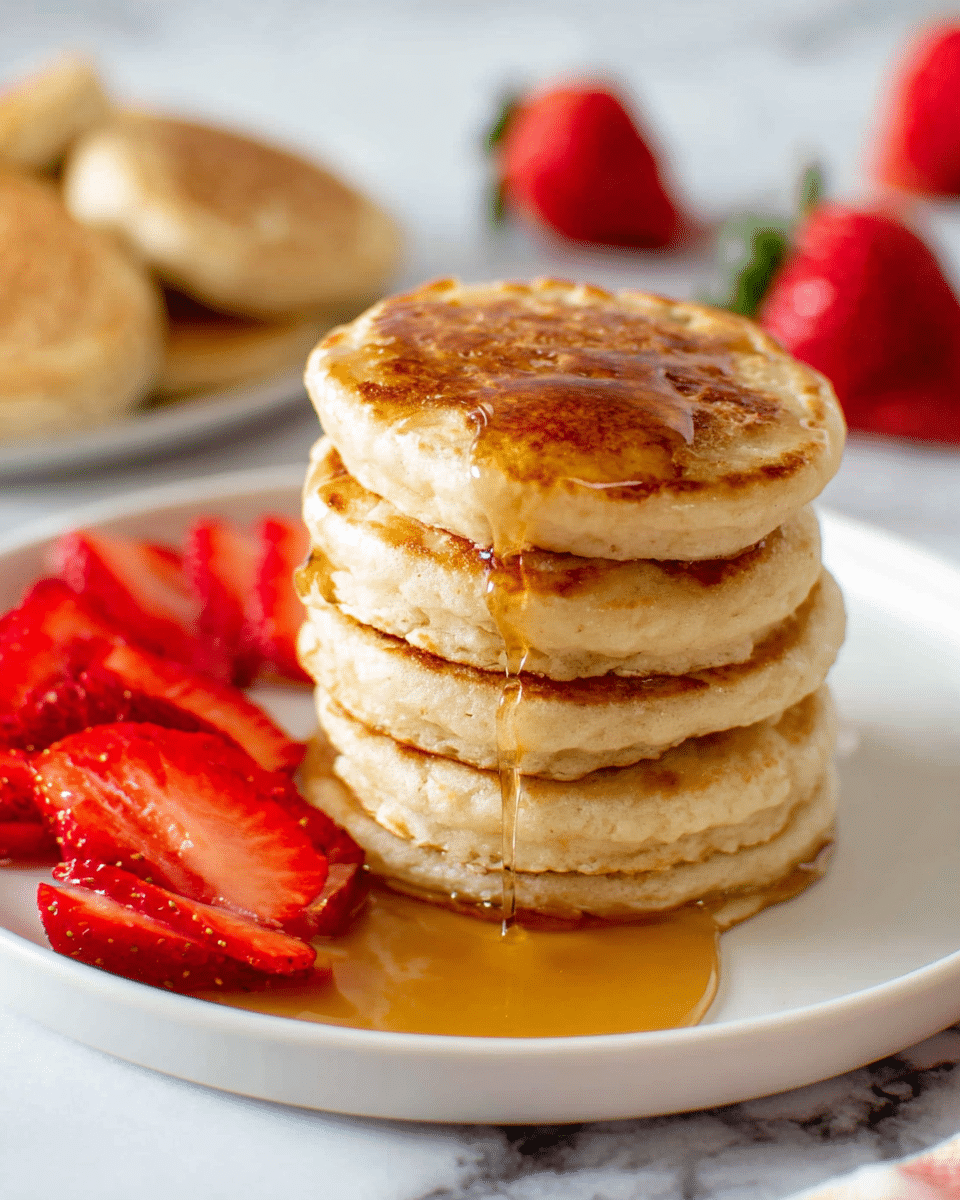 A stack of four thick, golden-brown pancakes sits in the center of a white plate, with syrup slowly dripping down their sides, creating a shiny, sticky texture. To the left of the stack are several sliced strawberries, bright red with small seeds visible, adding a fresh contrast. Behind the stack, there are additional pancakes scattered loosely, showing their soft, fluffy texture and light golden color on the edges. The plate is placed on a white marbled surface, and the background is softly blurred with more strawberries visible, adding vibrant red spots. photo taken with an iphone --ar 4:5 --v 7