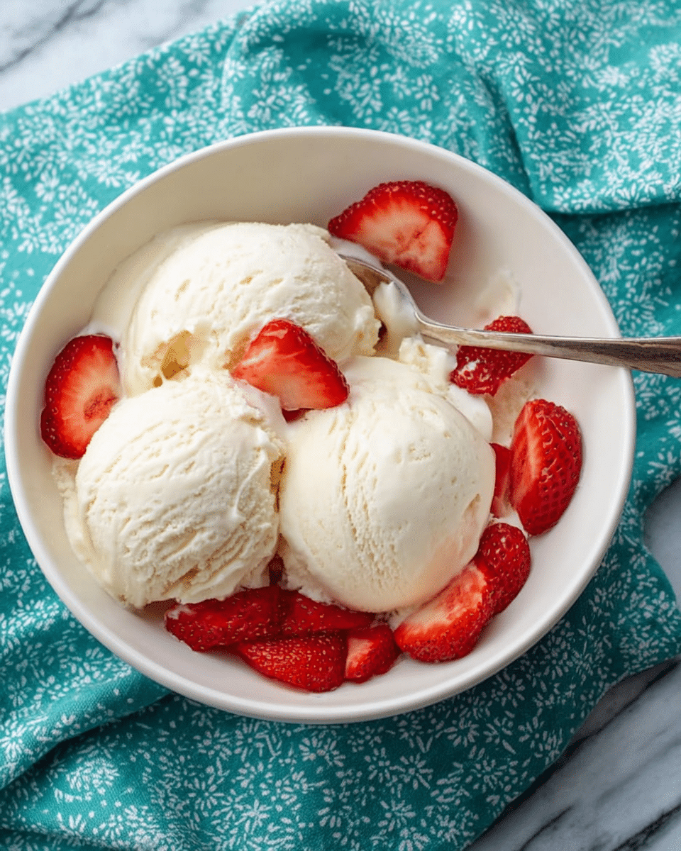 A white bowl filled with three scoops of creamy white vanilla ice cream with a smooth texture, topped with bright red sliced strawberries arranged around the edges. A silver spoon rests inside the bowl, partially submerged in the ice cream. The bowl is placed on a white marbled surface with a teal cloth featuring white patterns partially underneath it. Photo taken with an iphone --ar 4:5 --v 7