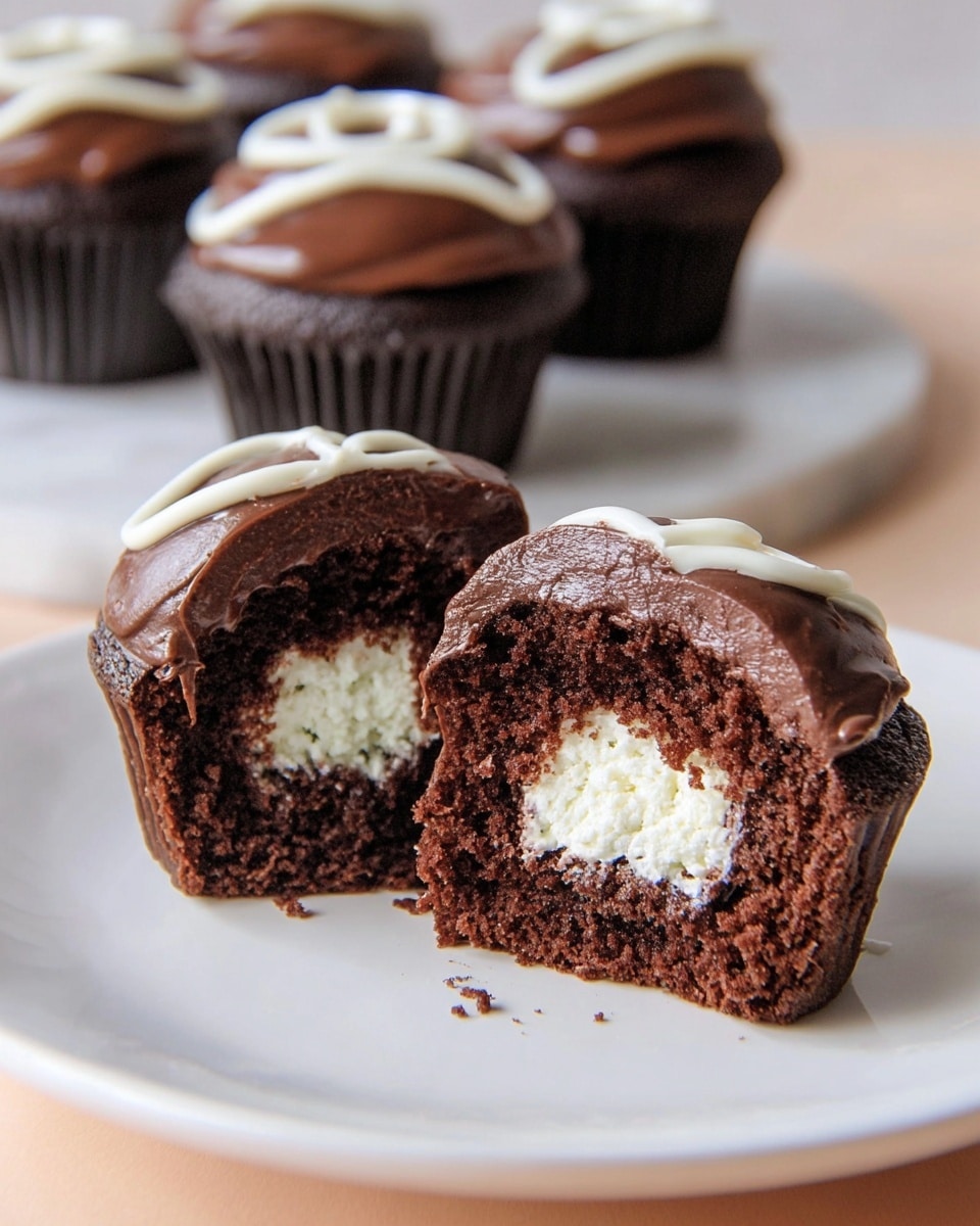 The image shows a white plate with a chocolate cupcake cut in half at the center. The cupcake has three layers: a moist dark brown chocolate cake base, a thick white creamy filling in the middle, and a smooth dark chocolate frosting as the top layer. There is a white icing swirl decoration on top of the frosting. In the background, there are whole chocolate cupcakes with the same dark chocolate frosting and white icing swirl, placed on a white marbled surface. The photo taken with an iphone --ar 4:5 --v 7