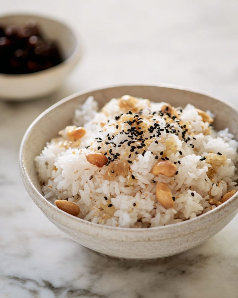 A bowl filled with white rice mixed with small to medium chunks of light brown chestnuts spread evenly throughout, sprinkled with black sesame seeds on top. The bowl is white with a rustic texture inside, set on a white marbled surface. In the background, there is a small white bowl with dark brown or black contents slightly blurred. The lighting is soft and natural, showing the texture of the rice and chestnuts clearly. photo taken with an iphone --ar 4:5 --v 7