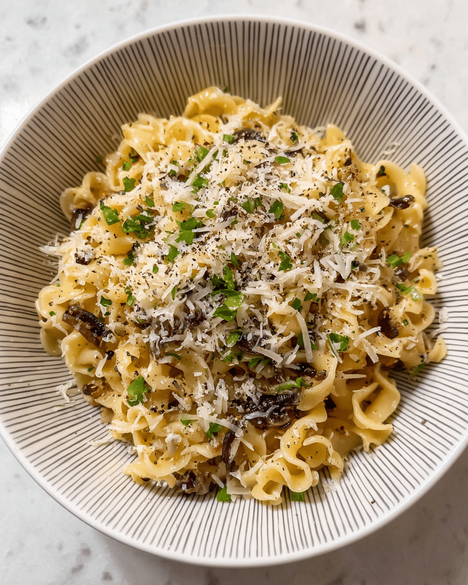 A close-up view of a bowl filled with ruffled-edged pasta coated in a light sauce, topped with finely shredded white cheese and scattered small green herb pieces. Darker small bits, possibly mushrooms or seasoning, are mixed throughout the pasta. The bowl is white with a gray patterned design inside. The background is a white marbled surface. photo taken with an iphone --ar 4:5 --v 7