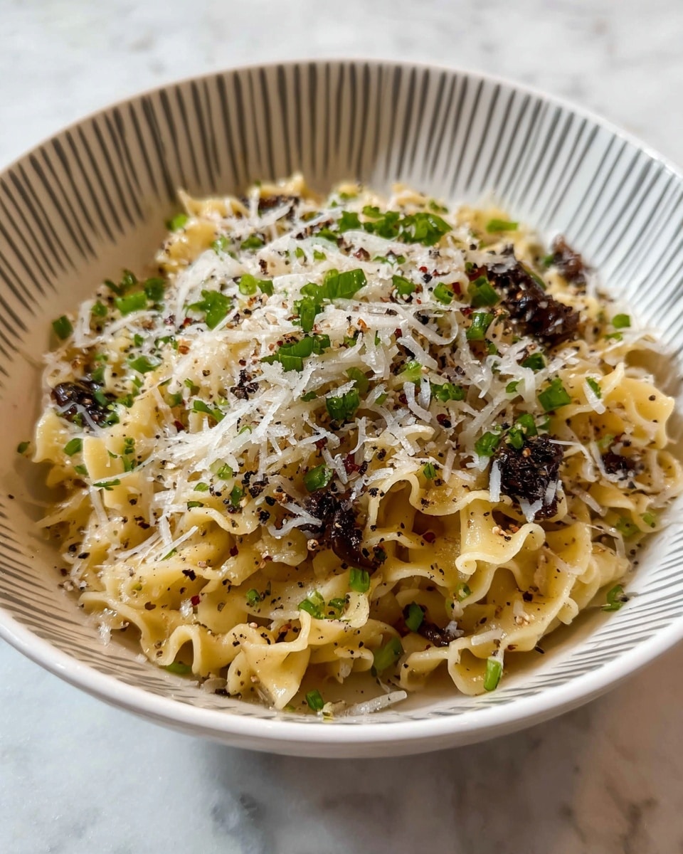 A bowl of curly pasta with a light yellow color forms the base layer, topped with small pieces of dark dried herbs or mushrooms scattered throughout. The pasta is sprinkled generously with finely shredded white cheese, creating a soft, snowy layer on top. Bright green chopped herbs are scattered lightly over the cheese, adding fresh pops of color. There are visible black pepper specks and other small seasonings spread evenly, giving a textured look to the dish. The pasta sits in a white bowl with a simple gray curved pattern along the inner side, and the background is a white marbled surface. Photo taken with an iphone --ar 4:5 --v 7