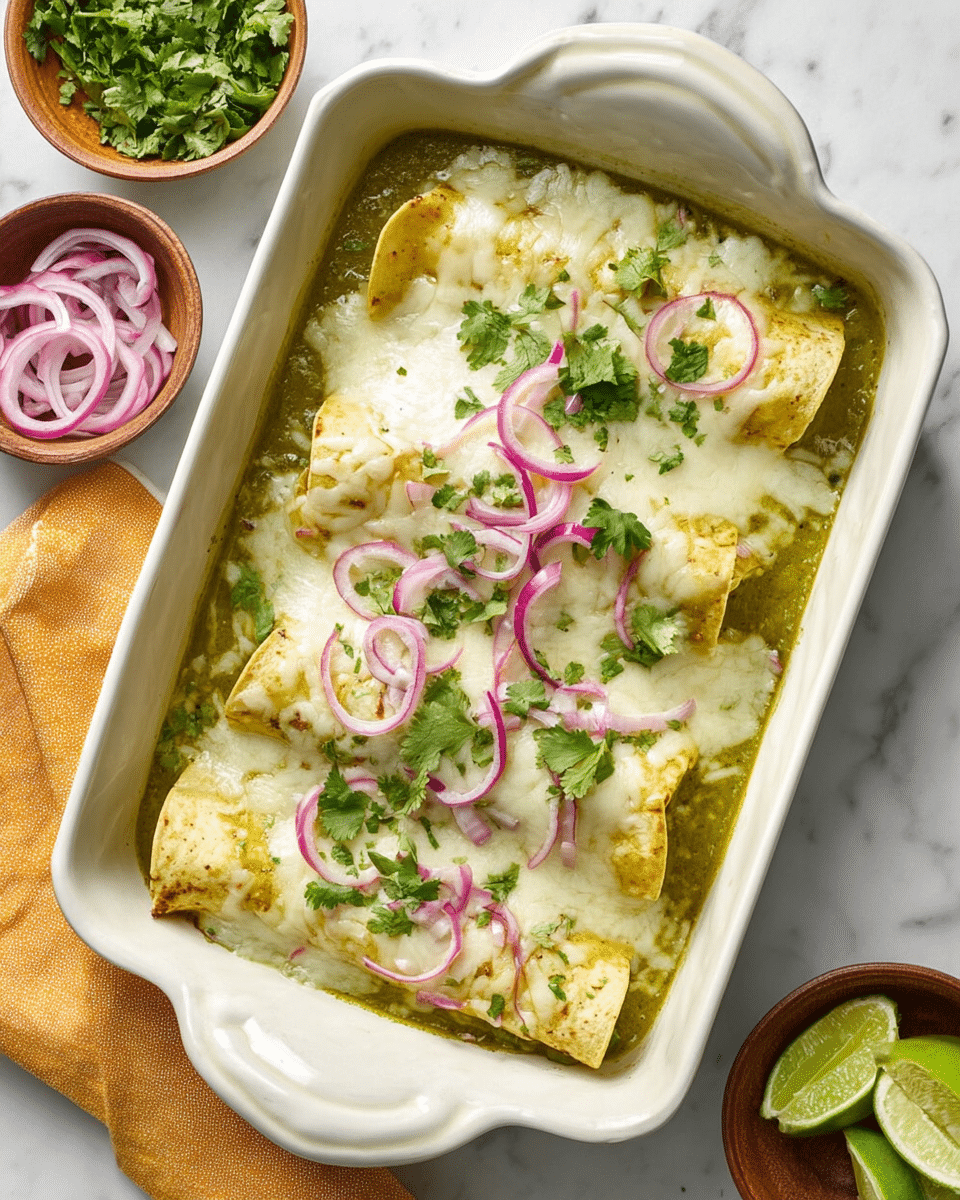 A white baking dish filled with two folded yellow tortillas covered with melted white cheese, sitting in a green sauce base. On top, thin rings of red onion and small green cilantro leaves are scattered evenly, adding color contrast. The dish rests on a white marbled surface with small brown bowls beside it holding fresh cilantro and sliced red onion, and lime wedges are visible nearby. photo taken with an iphone --ar 4:5 --v 7