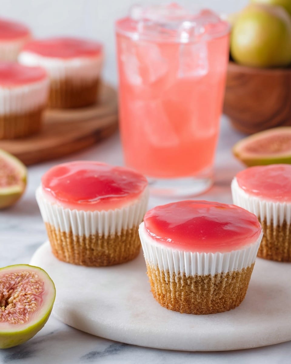 Three cupcakes are shown on a round white marble board, each with three layers; the bottom layer is a light brown cake, the middle layer is white creamy frosting, and the top layer is a glossy, smooth bright pink jelly. The cupcakes are in white paper liners. In the background, there is a clear glass filled with pink drink and ice cubes and some whole and halved guavas with pink insides resting near a wooden bowl. The setting is on a white marbled surface. photo taken with an iphone --ar 4:5 --v 7