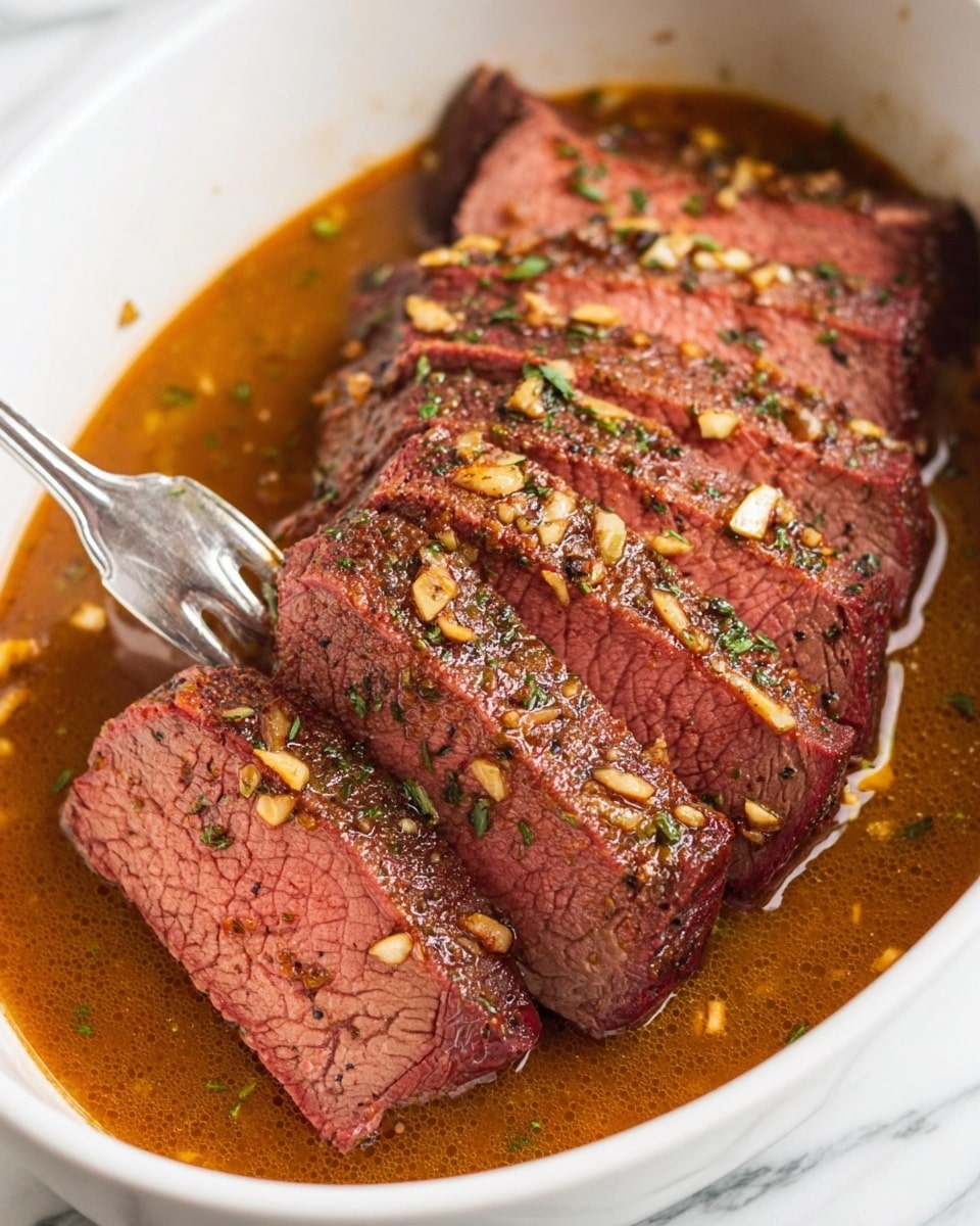 A white bowl holds a sliced beef roast with about eight visible thick slices arranged close together. The beef is medium-rare with a pink center and a dark brown crust sprinkled with small garlic pieces and green herbs. The meat sits in a rich, brown sauce that fills the bowl around the beef, showing a glossy texture. A fork is stuck into one slice near the left side. The background is a white marbled texture. photo taken with an iphone --ar 4:5 --v 7