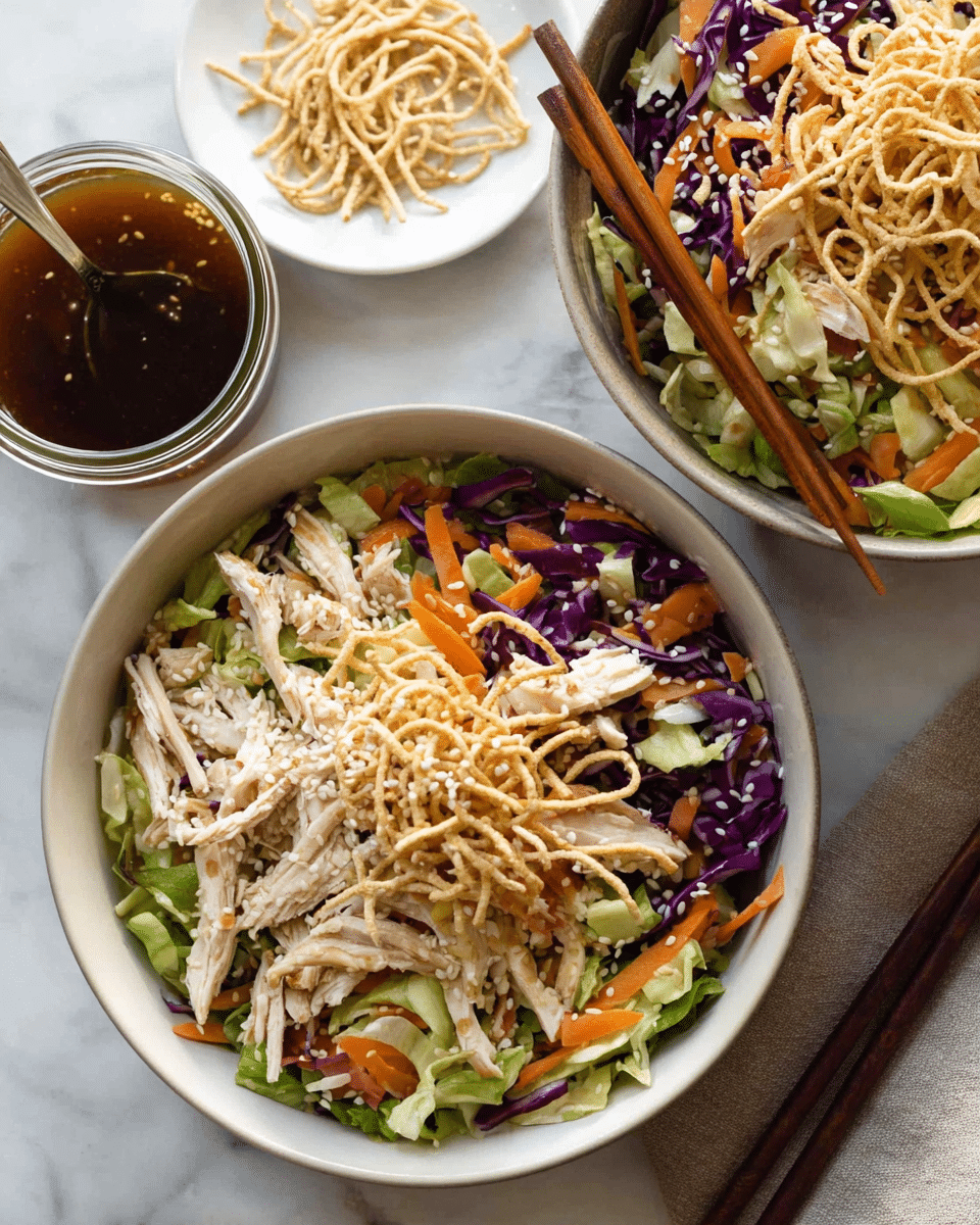Two white bowls filled with a salad layered starting with green and purple shredded cabbage and sliced orange carrots at the bottom. On top of that are light-colored shredded chicken pieces scattered evenly. The next layer consists of thin, light brown crispy noodle sticks sprinkled over the chicken. White sesame seeds are sprinkled on top of the noodle sticks. Wooden chopsticks rest on the edge of the top bowl. Nearby, a small clear jar holds a dark brown dressing with a glossy texture, and a small white plate contains extra sesame seeds and a few noodle sticks, all set on a white marbled surface. photo taken with an iphone --ar 4:5 --v 7